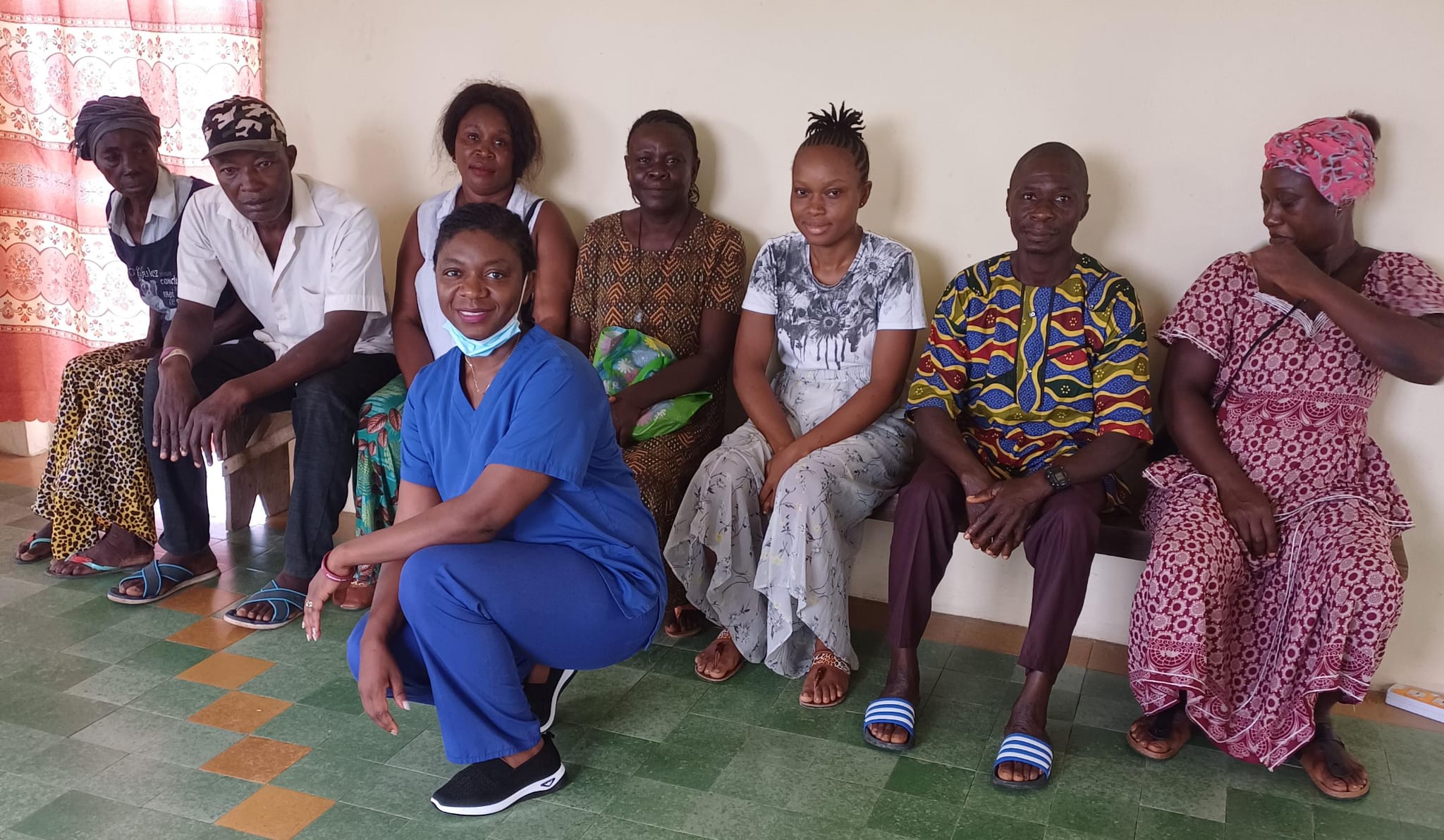 Adama Fofana, The Breathe Well Initiative co-founder, knelt down in front of sitting patients at the organisation's health care clinic in Bo, Sierra Leone.