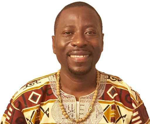 James, a black man with close-cut hair wearing Sierra Leonean attire, is smiling 